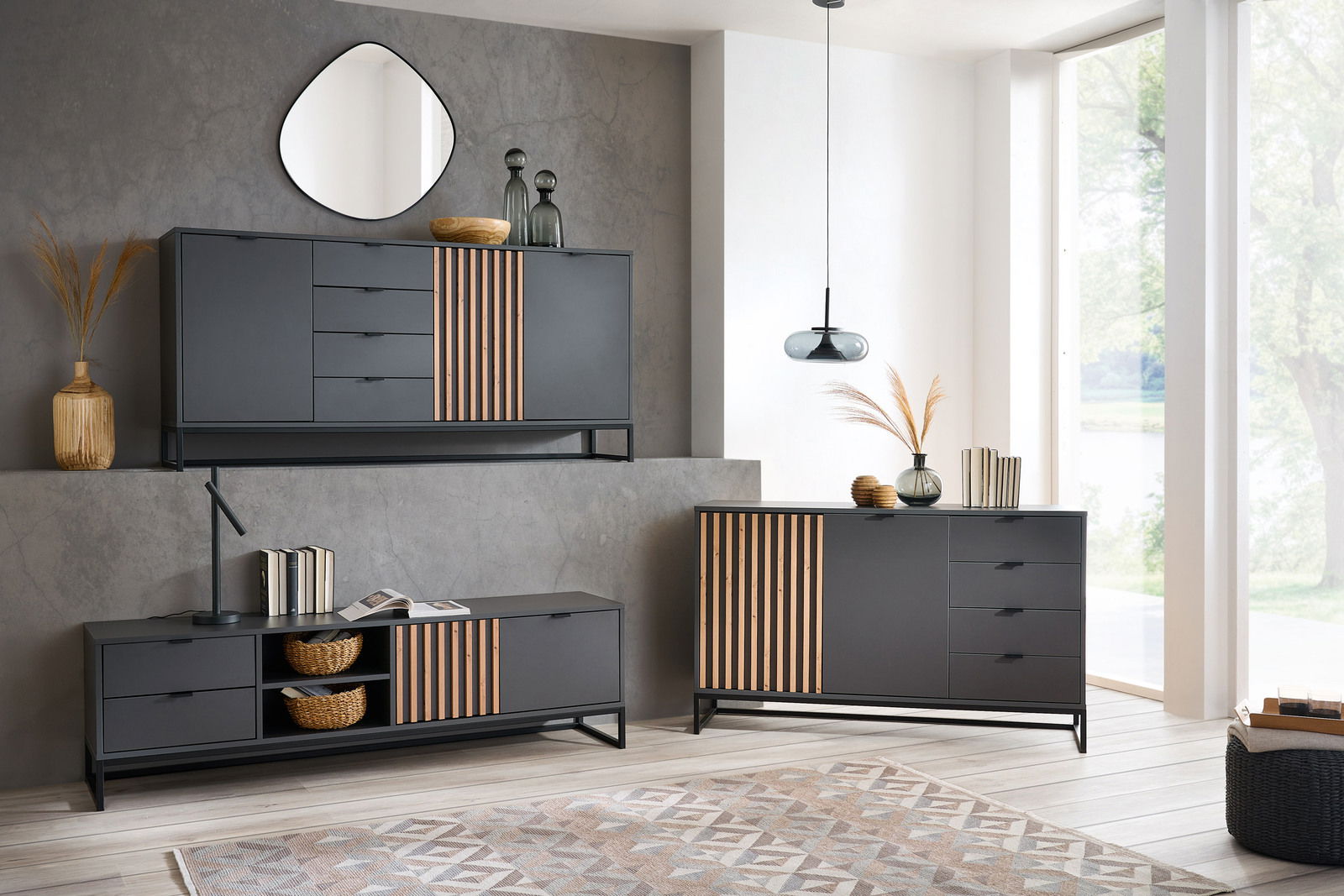 Moderne Wohnzimmermöbel in dunklem Design mit Holzakzenten, bestehend aus einem Sideboard, einem XL-Sideboard und einem TV-Lowboard, aus der Perspektive eines hellen, geräumigen Raumes mit großen Fenstern.