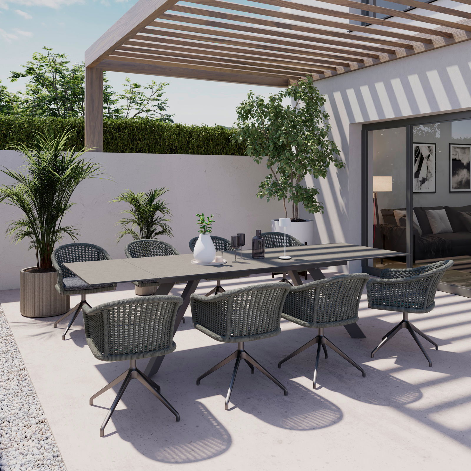 Moderner Gartentisch mit sechs Stühlen auf einer Terrasse, umgeben von Pflanzen, aus der Perspektive von schräg oben fotografiert.