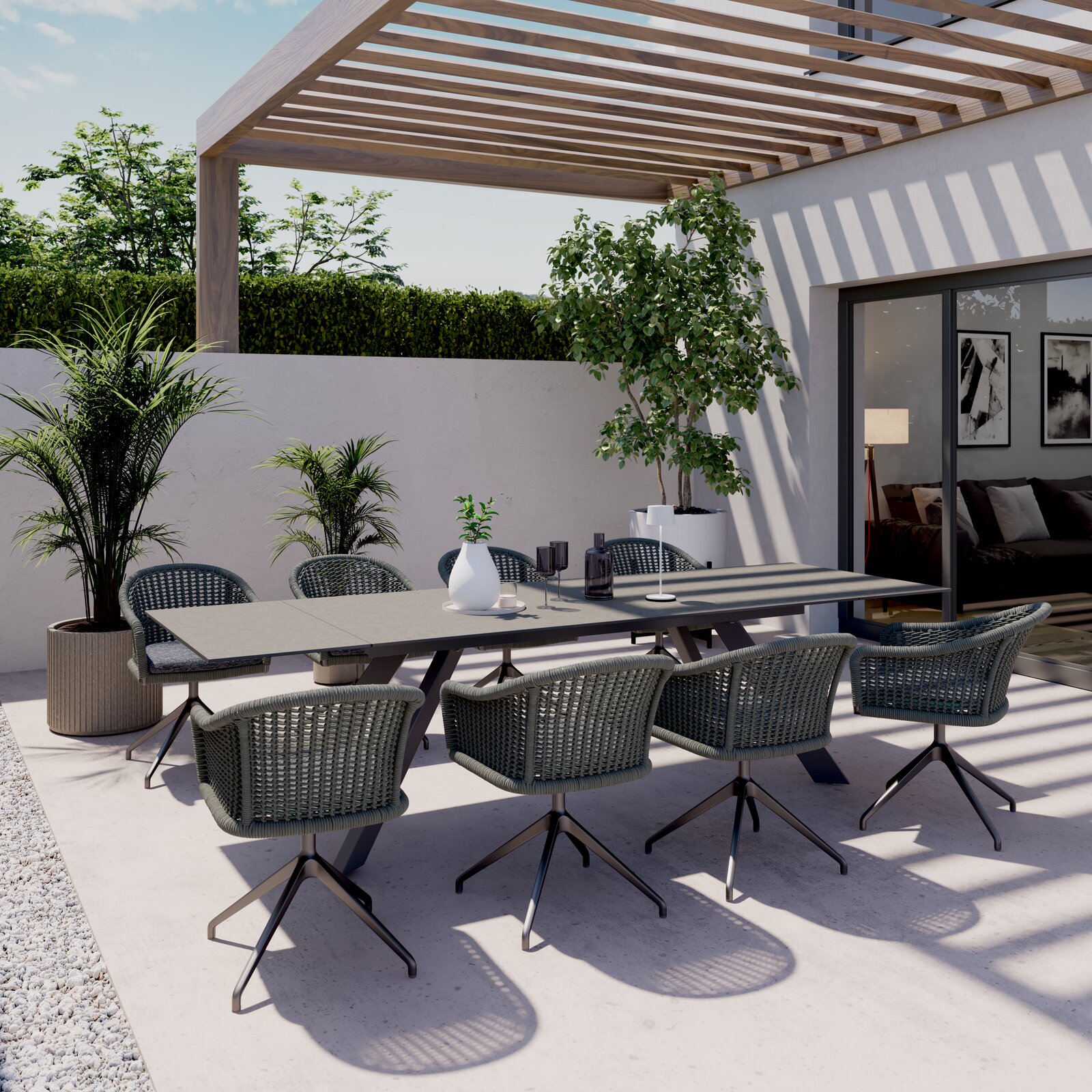 Moderner Gartentisch mit sechs Stühlen auf einer Terrasse, umgeben von Pflanzen, aus der Perspektive von schräg oben fotografiert.