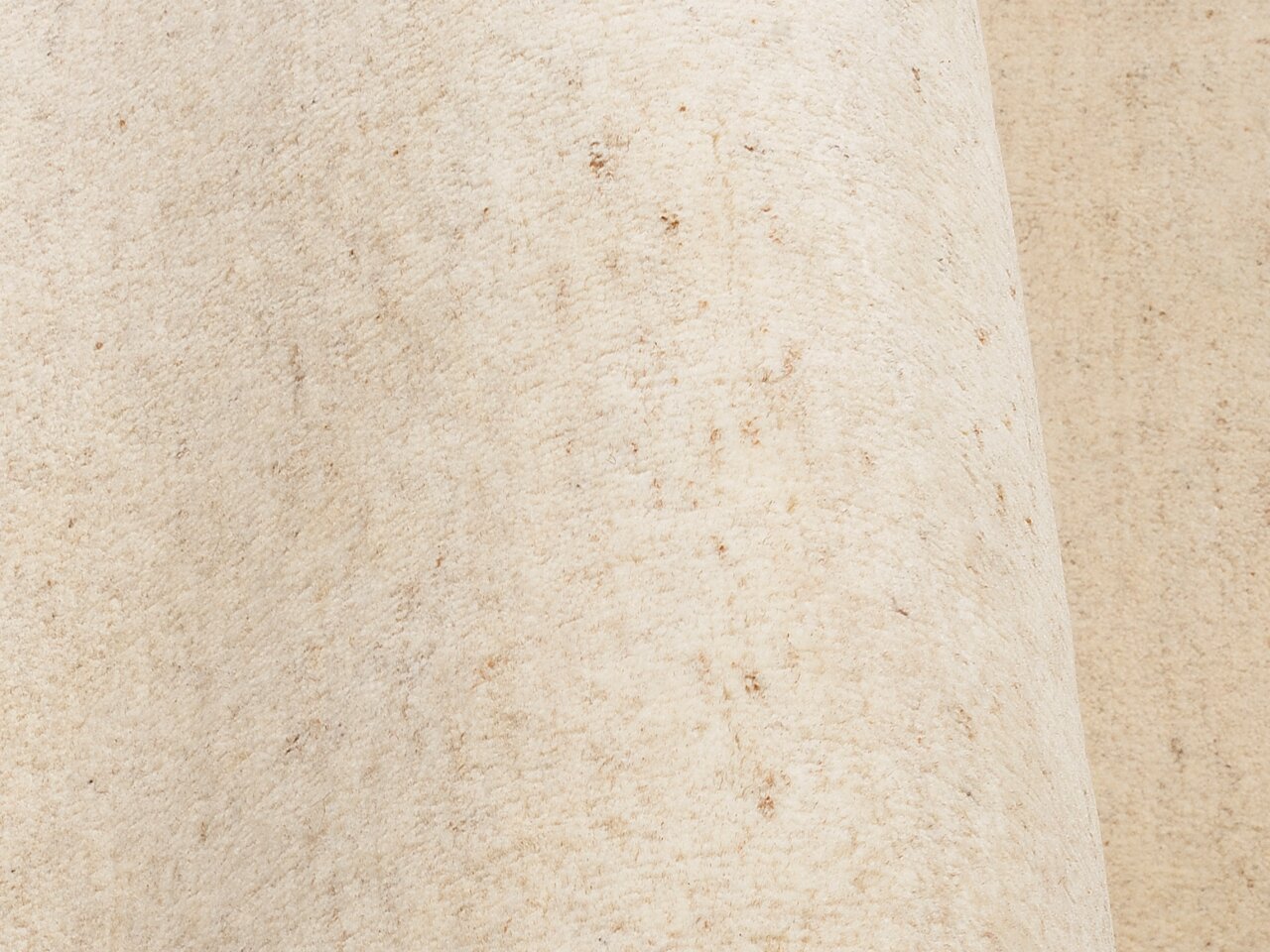 Nahaufnahme eines cremefarbenen Wollteppichs mit leichter Textur.