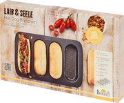 Verpackung eines Hot Dog Brötchen-Blechs mit drei geformten Brötchen und einem belegten Hot Dog, fotografiert aus einer leicht schrägen Perspektive.