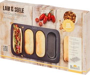 Verpackung eines Hot Dog Brötchen-Blechs mit drei geformten Brötchen und einem belegten Hot Dog, fotografiert aus einer leicht schrägen Perspektive.