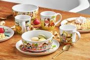 Servies voor kinderen met bouwplaatsmotieven, bestaande uit een kopje, een kom en een bord, opgesteld op een houten tafel. Vooraanzicht.