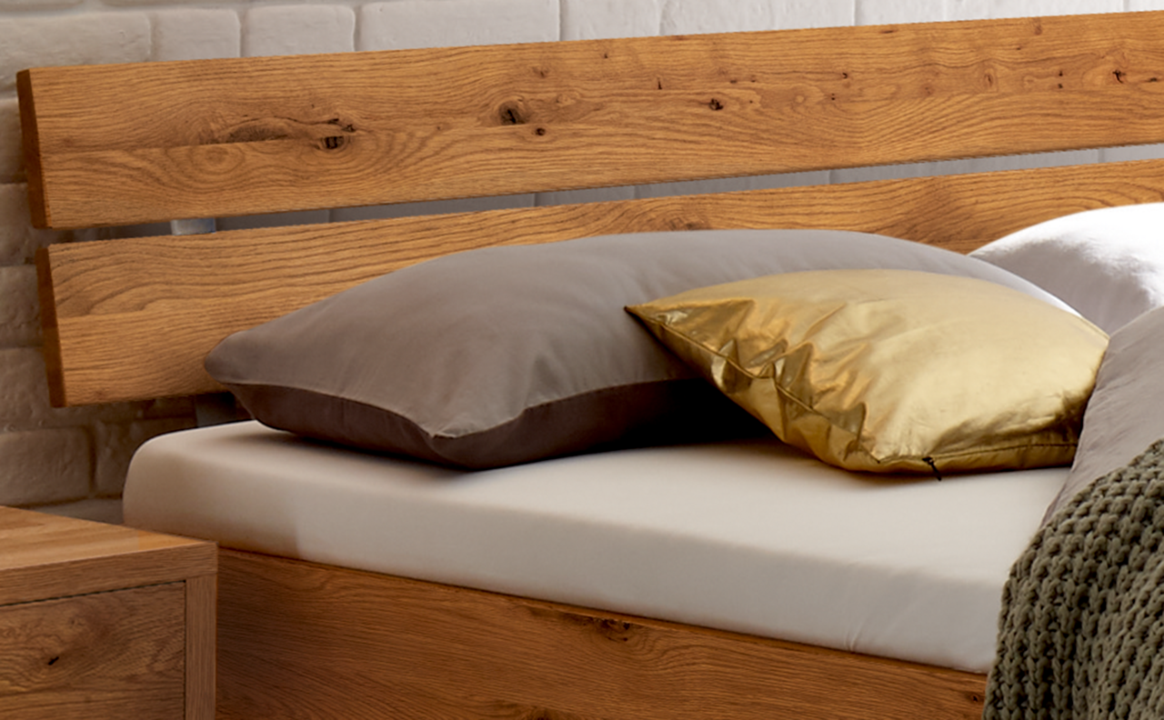 Holz-Kopfteil mit natürlicher Maserung, seitliche Perspektive, dekoriert mit Kissen.