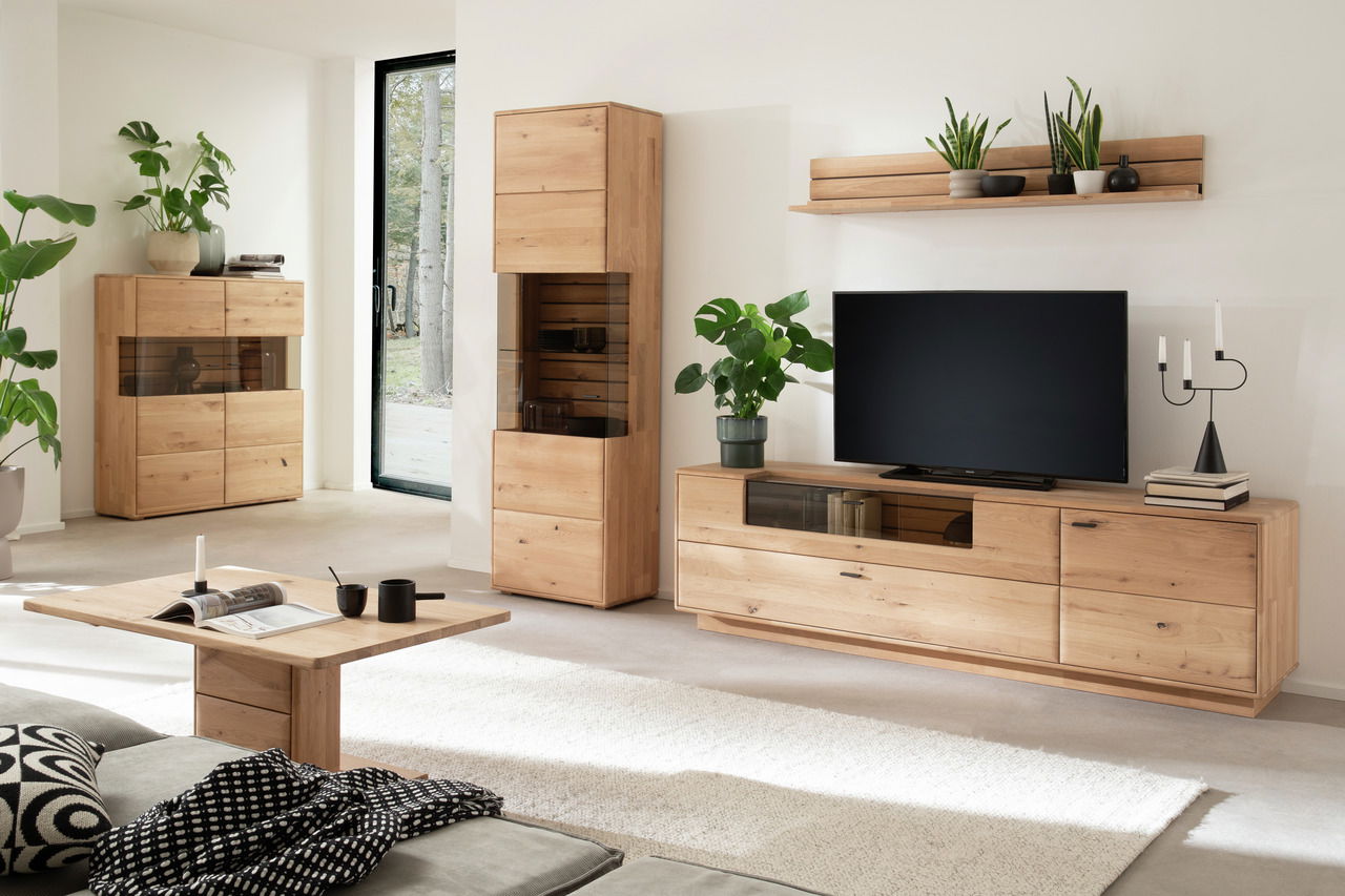 Linea Natura Highboard GEORGIA Modernes Wohnzimmer mit einem Highboard aus Holz, umgeben von Pflanzen und stilvollen Dekorationen, seitliche Perspektive.