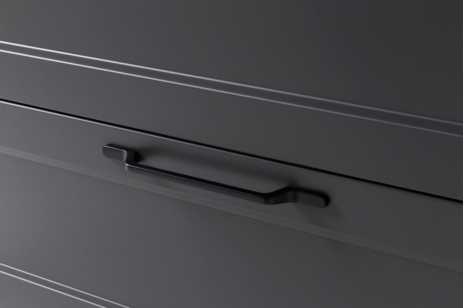 Nahaufnahme eines modernen, dunkelgrauen Waschtisch-Schranks mit einem eleganten schwarzen Griff, seitliche Perspektive