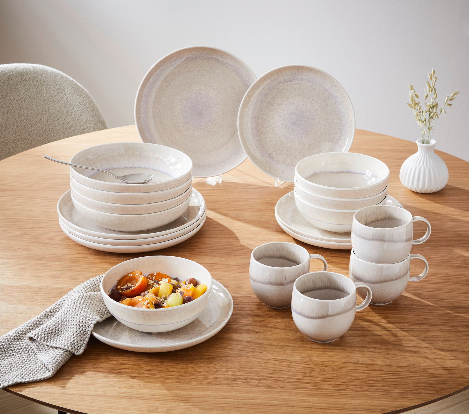 Tafelservice 8-tlg. auf einem Holztisch, bestehend aus Tellern, Schalen und Tassen in sanften Beige- und Grautönen, seitliche Perspektive.
