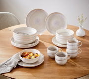 Tafelservice 8-tlg. auf einem Holztisch, bestehend aus Tellern, Schalen und Tassen in sanften Beige- und Grautönen, seitliche Perspektive.
