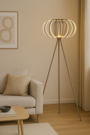 Moderne Stehleuchte mit dreibeinigem Stativ und dekorativem, leuchtendem Lampenschirm in einem gemütlichen Wohnzimmer, seitliche Perspektive.