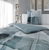 Moderne Wendebettwäsche in Blau- und Grautönen mit geometrischem Muster, auf einem stilvoll eingerichteten Bett in einem hellen Raum, seitliche Perspektive.