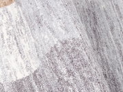 Nahaufnahme eines grauen und weißen Frisé-Teppichs mit weicher Textur, von der Seite betrachtet.