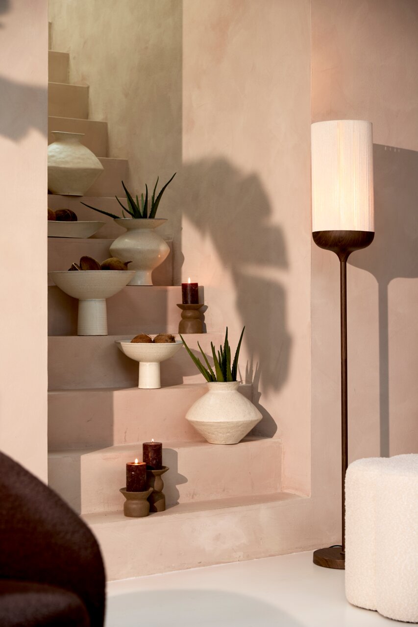 Light&Living Staande lamp DANIA Stijlvolle staande lamp met een cilindervormige, witte lampenkap en een donkere houten voet, naast een versierde trap met kaarsen, schalen en planten, zijaanzicht