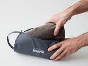 Tempur Reisekissen in einer grauen Tasche, von zwei Händen gehalten, seitliche Perspektive