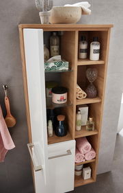 Midischrank aus Holz mit offenen Regalfächern, gefüllt mit Pflegeprodukten und Handtüchern, aus der Perspektive von oben fotografiert.