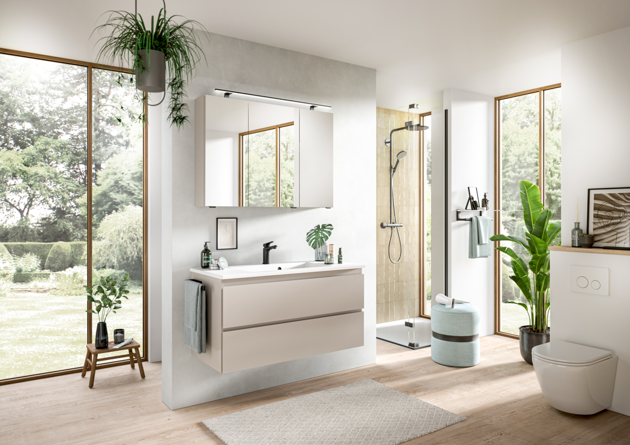 Moderne Badkombination mit Waschbecken, Spiegel und Schubladen in einem hellen Badezimmer mit Blick auf den Garten.