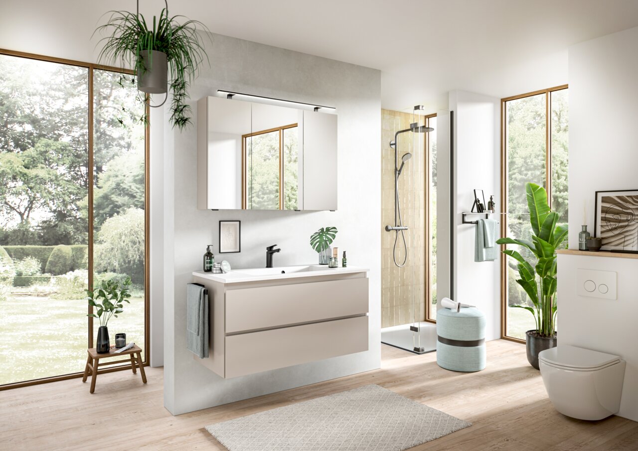 Moderne Badkombination mit Waschbecken, Spiegel und Schubladen in einem hellen Badezimmer mit Blick auf den Garten.