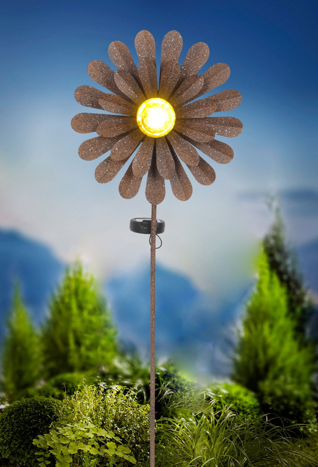 Solarleuchte in Form einer Blume mit gelbem Licht in der Mitte, auf einem Stab montiert, vor einem Hintergrund aus grünen Pflanzen, seitliche Perspektive.