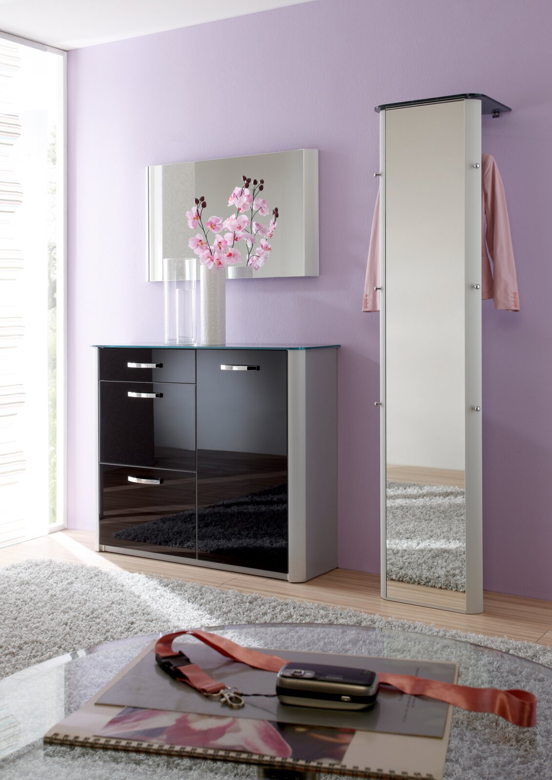 Moderne Garderobe mit Spiegel und Schrank in einem stilvollen Raum mit lila Wand, aus der Perspektive von vorne betrachtet.