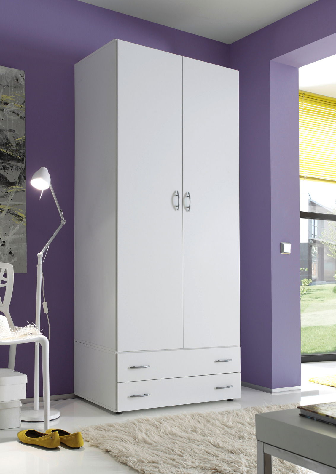 Weißer, zweitüriger Drehtürenschrank mit zwei Schubladen, in einem modernen Raum mit lila Wand und Blick aus dem Fenster.