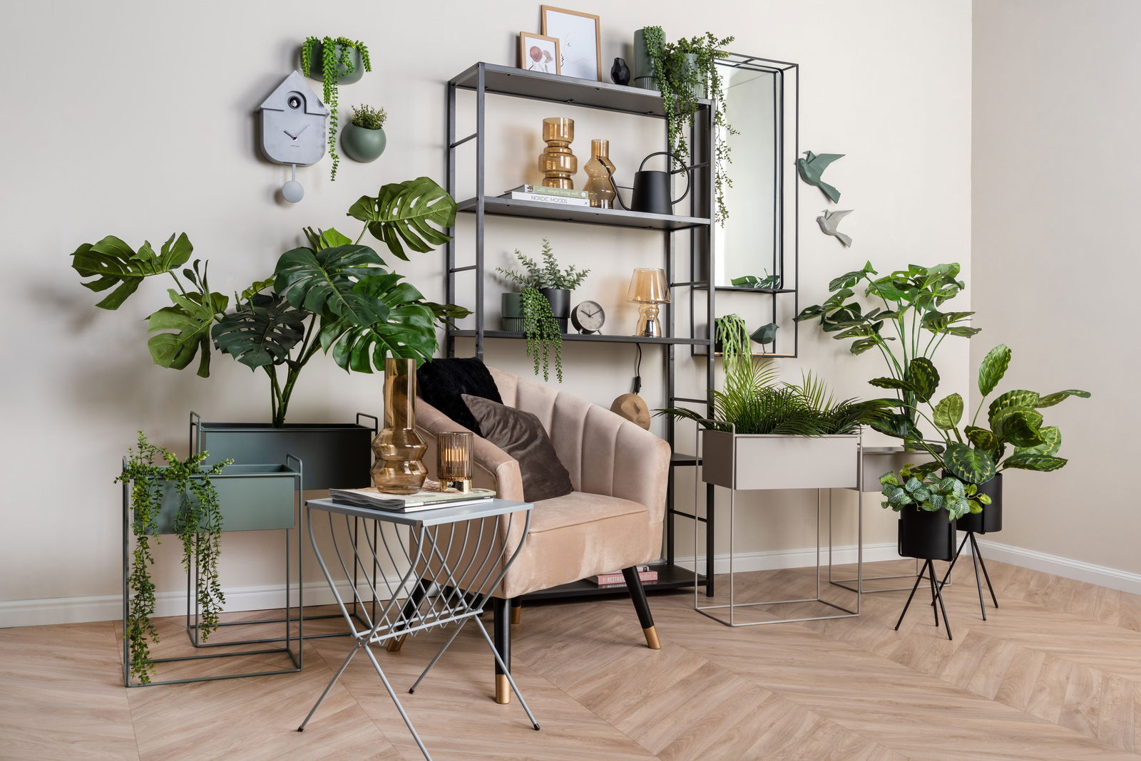 Moderne Wanduhr in Form eines Vogelhauses, an einer hellen Wand hängend, umgeben von grünen Pflanzen und stilvollen Dekorationen. Perspektive: Frontalansicht.