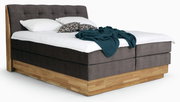 Boxspringbett mit braunem Stoffbezug und Holzrahmen, seitliche Perspektive