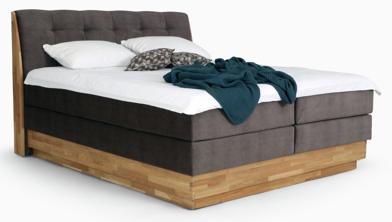 Boxspringbett mit braunem Stoffbezug und Holzrahmen, seitliche Perspektive