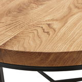 Nahaufnahme eines runden Beistelltisches mit einer Holzoberfläche und einem schwarzen Metallgestell, Perspektive von oben.