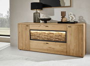 Frontale Ansicht eines modernen Sideboards aus Holz mit dekorativer Steinoptik und Beleuchtung in der Mitte, dekoriert mit einer Lampe und Kunstobjekten.