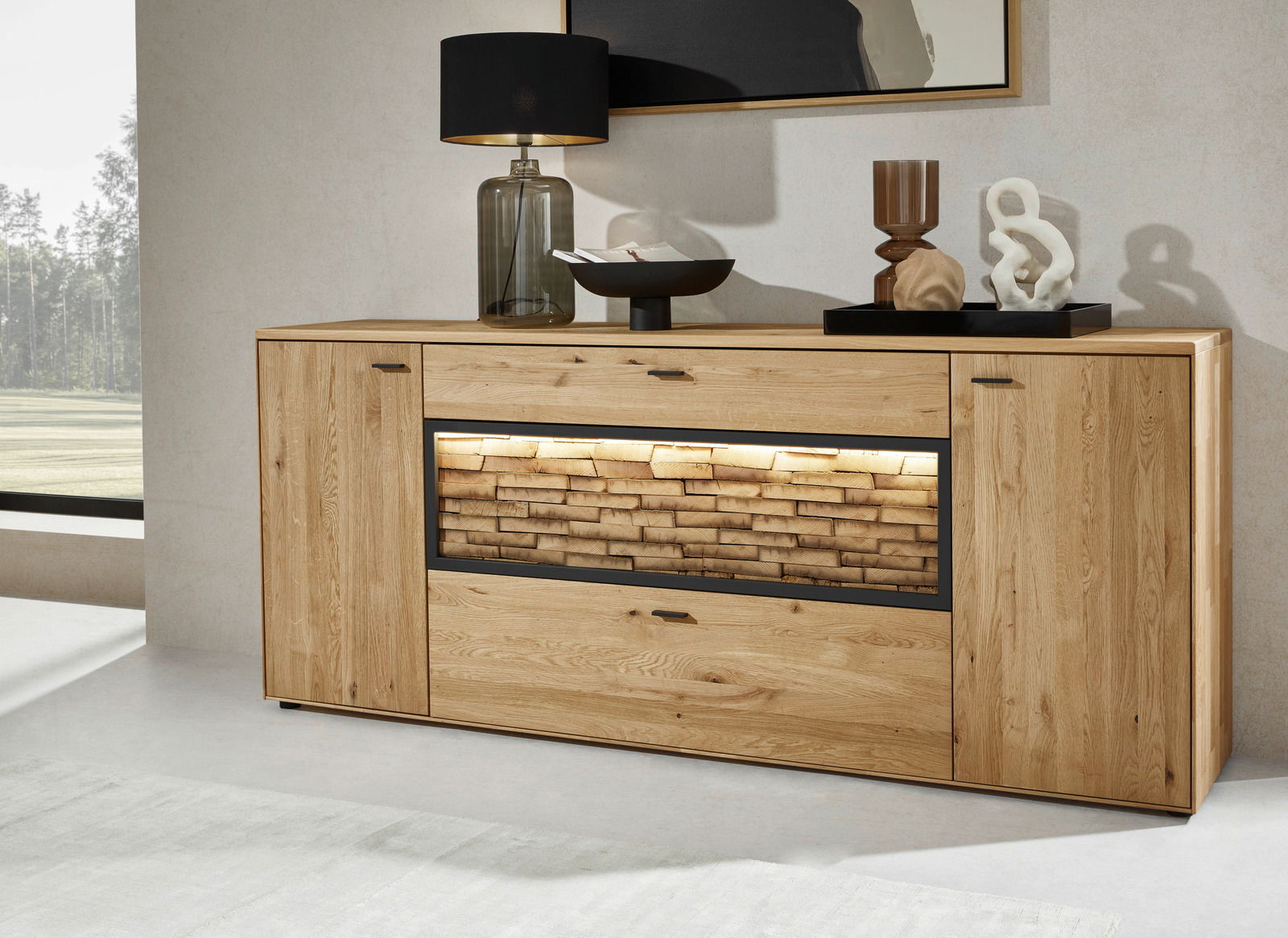 Frontale Ansicht eines modernen Sideboards aus Holz mit dekorativer Steinoptik und Beleuchtung in der Mitte, dekoriert mit einer Lampe und Kunstobjekten.