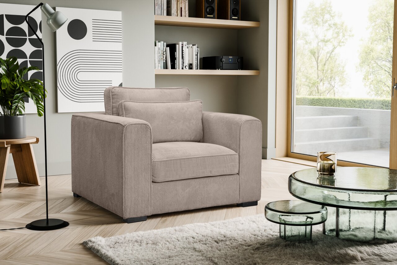 Beiger, gepolsterter Cord-Sessel mit breiten Armlehnen und Rückenkissen im modernen Wohnzimmer neben Glas-Couchtisch und Fensterfront, Perspektive: leicht schräg von vorne links.