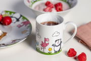 Kindergeschirr-Set mit Tasse, Teller und Schüssel, verziert mit bunten Tiermotiven, aus der Perspektive von vorne fotografiert.
