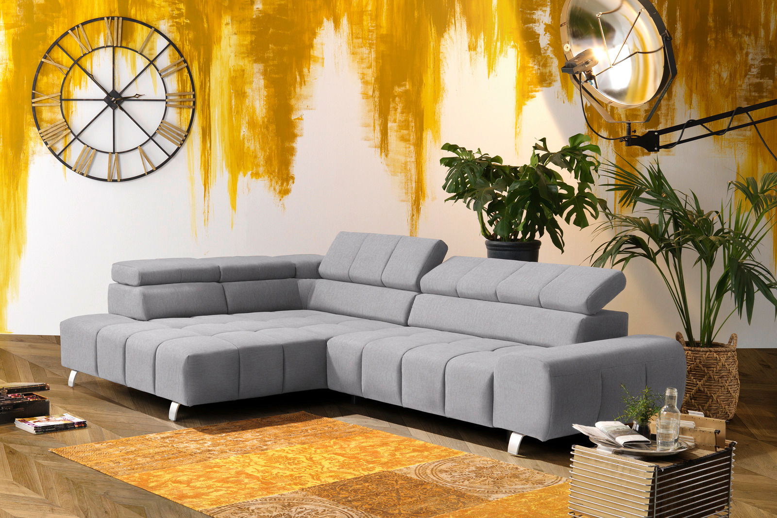 Graues Ecksofa mit Ottomane links in modernem Wohnzimmer, seitliche Perspektive.