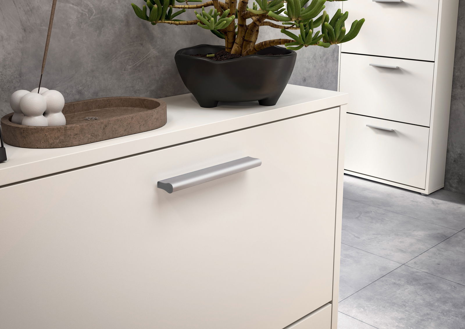 Nahaufnahme eines weißen Schuhkippers mit silbernem Griff, dekoriert mit einer Pflanze und Dekorationsgegenständen, seitliche Perspektive.