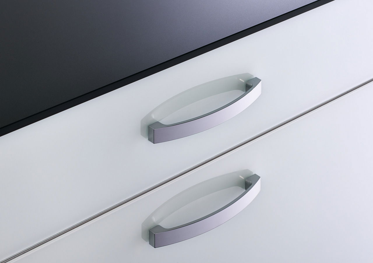 Nahaufnahme von zwei silbernen Griffen an einem weißen Schuhschrank, von oben betrachtet.