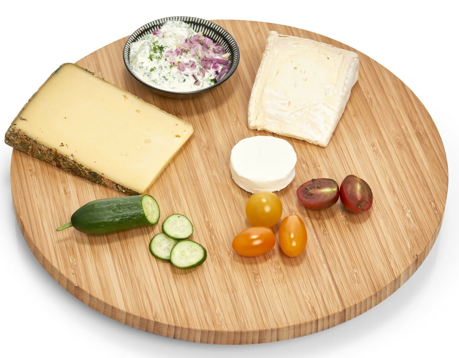 Rundes Drehkabinett aus Holz mit verschiedenen Käsesorten, Gurkenscheiben, Tomaten und einem Dip, von oben betrachtet.