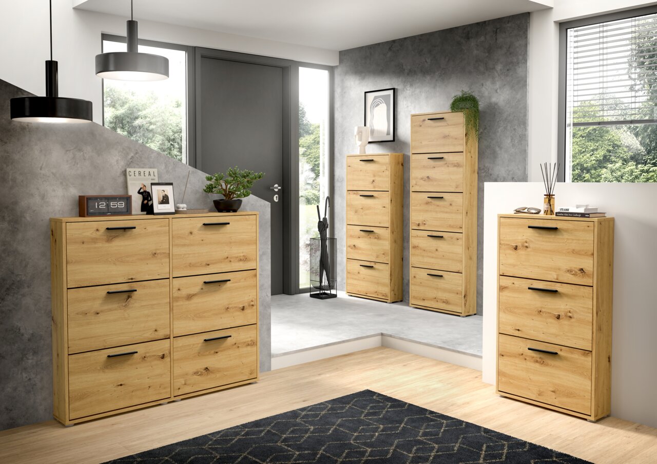 Schuhkipper aus Holz mit drei Klappen, in einem modernen Raum mit grauer Wand und großen Fenstern, aus der Vorderansicht fotografiert.