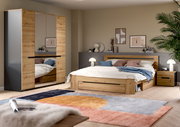 Modernes Schlafzimmer-Set mit Holzbett inklusive Stauraum, Nachttisch und Kleiderschrank mit Spiegeltüren in Eiche-Optik und dunklen Akzenten, fotografiert in schräger Frontansicht aus leicht erhöhter Perspektive.