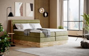 Modernes Boxspringbett in einem stilvollen Schlafzimmer mit grüner Polsterung und Holzdetails, seitliche Perspektive