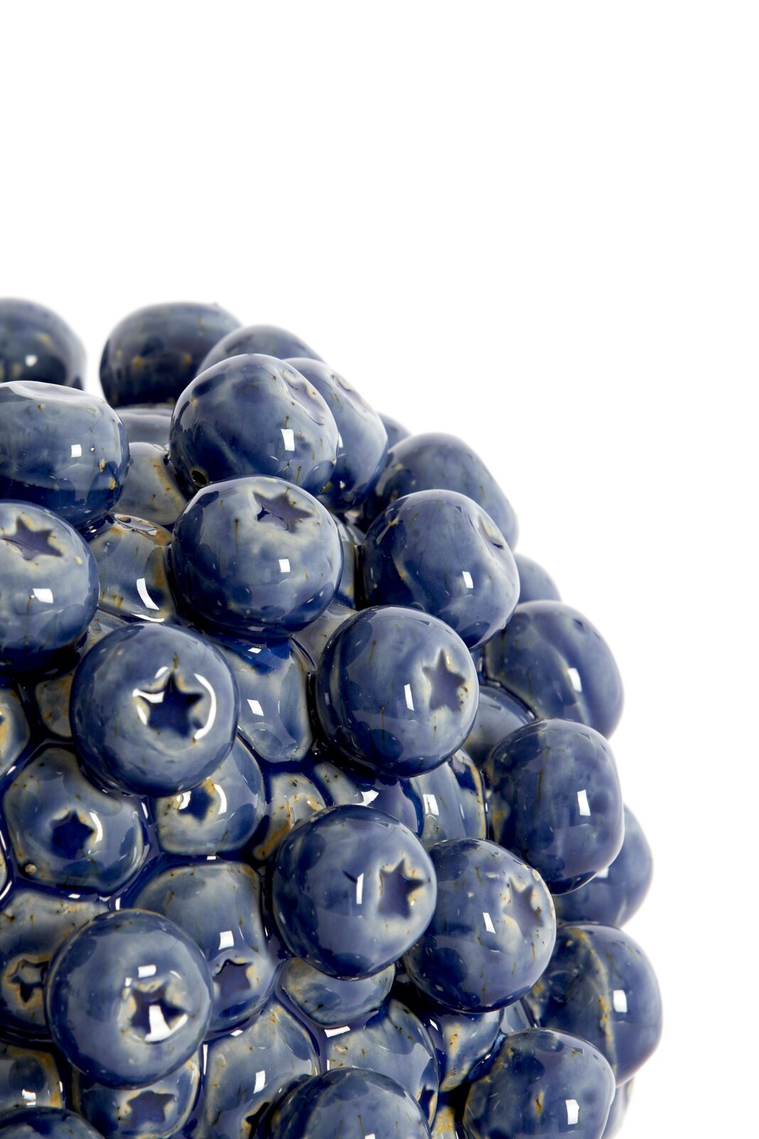 Nahaufnahme eines blauen, glänzenden Lampenfußes mit einer Oberfläche, die an eine Ansammlung von Beeren erinnert.