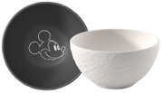 Weiße Keramikschüssel mit strukturierter Außenseite neben schwarzem Teller mit Mickey-Mouse-Kopf-Umriss, seitliche Perspektive