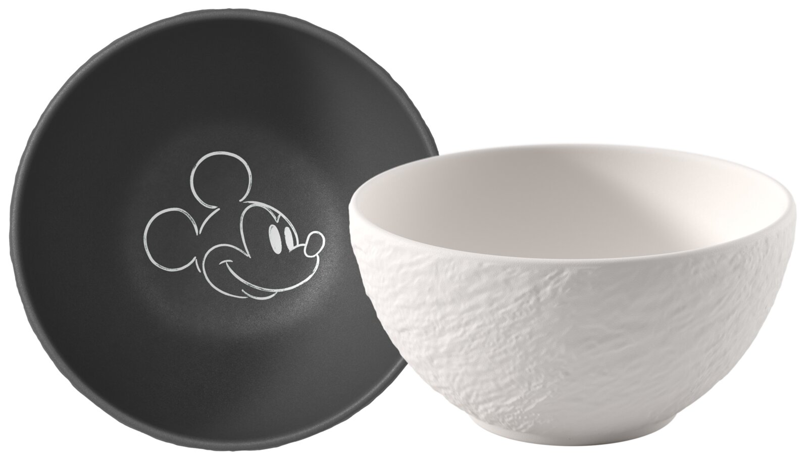 Weiße Keramikschüssel mit strukturierter Außenseite neben schwarzem Teller mit Mickey-Mouse-Kopf-Umriss, seitliche Perspektive