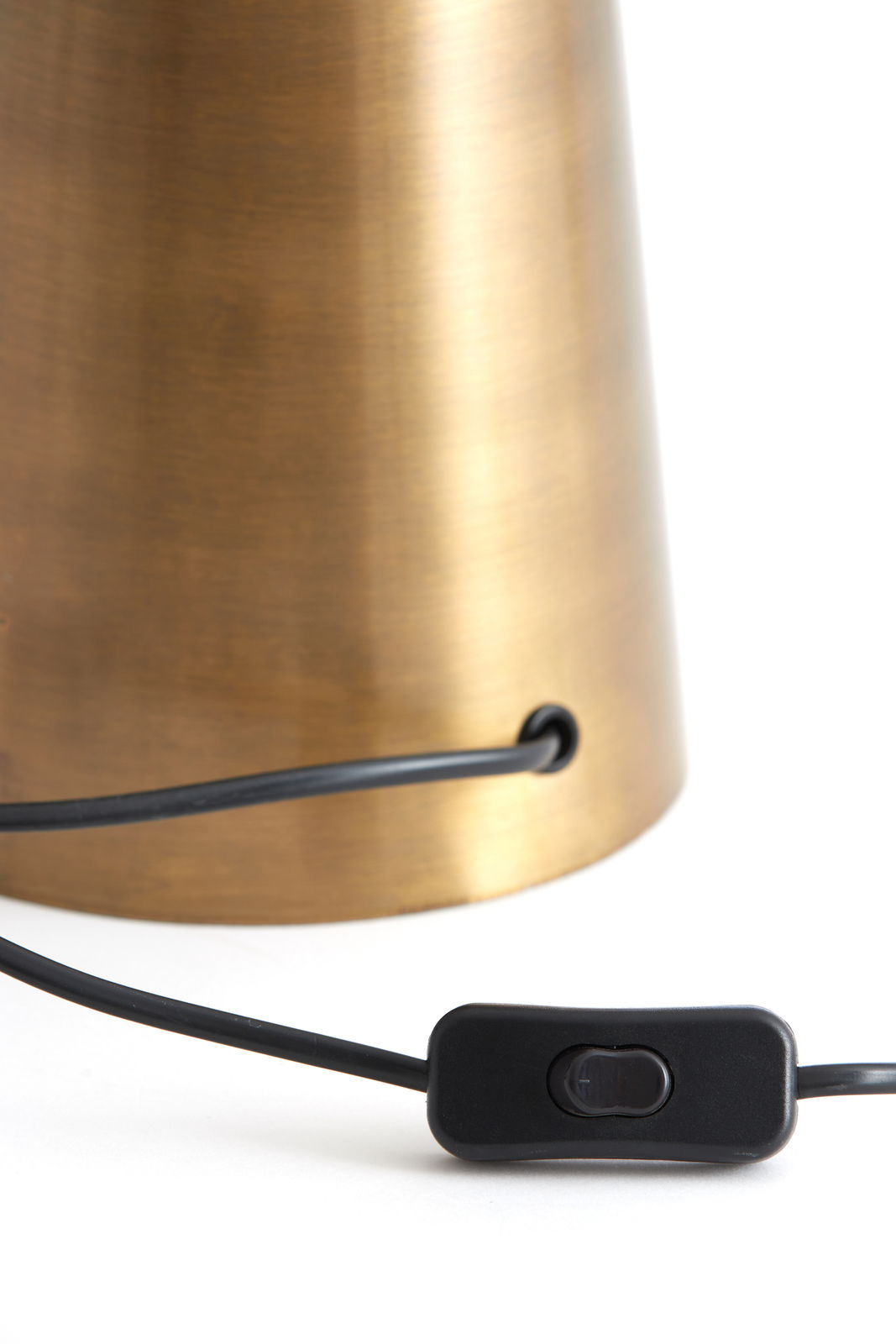 Nahaufnahme eines Lampenfußes aus gebürstetem Metall mit einem schwarzen Kabel und einem Schalter, seitliche Perspektive.