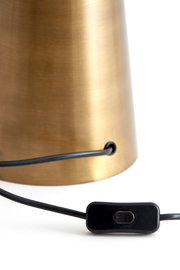 Nahaufnahme eines Lampenfußes aus gebürstetem Metall mit einem schwarzen Kabel und einem Schalter, seitliche Perspektive.