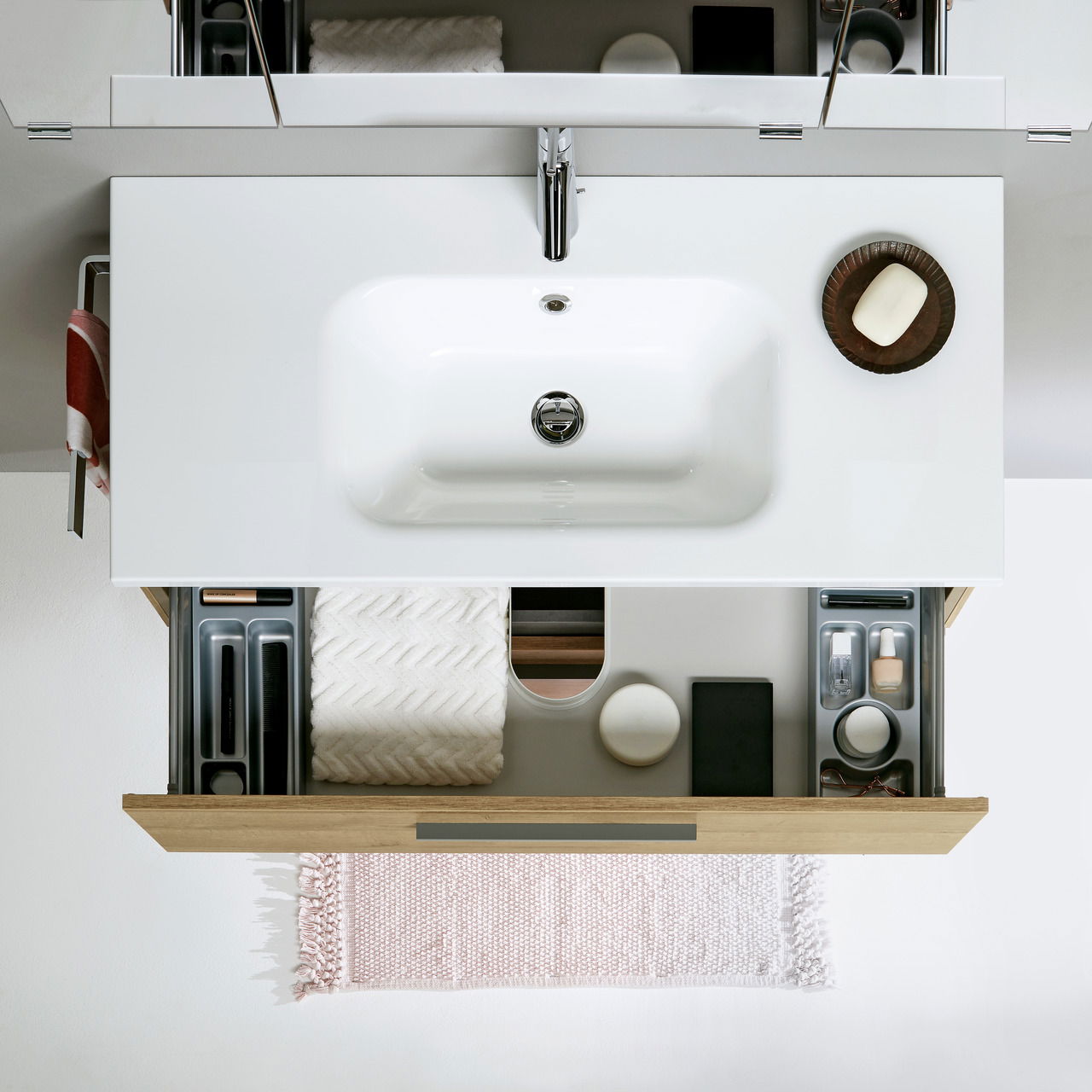 Badezimmerkombination von oben mit Waschbecken, geöffneter Schublade und Accessoires.