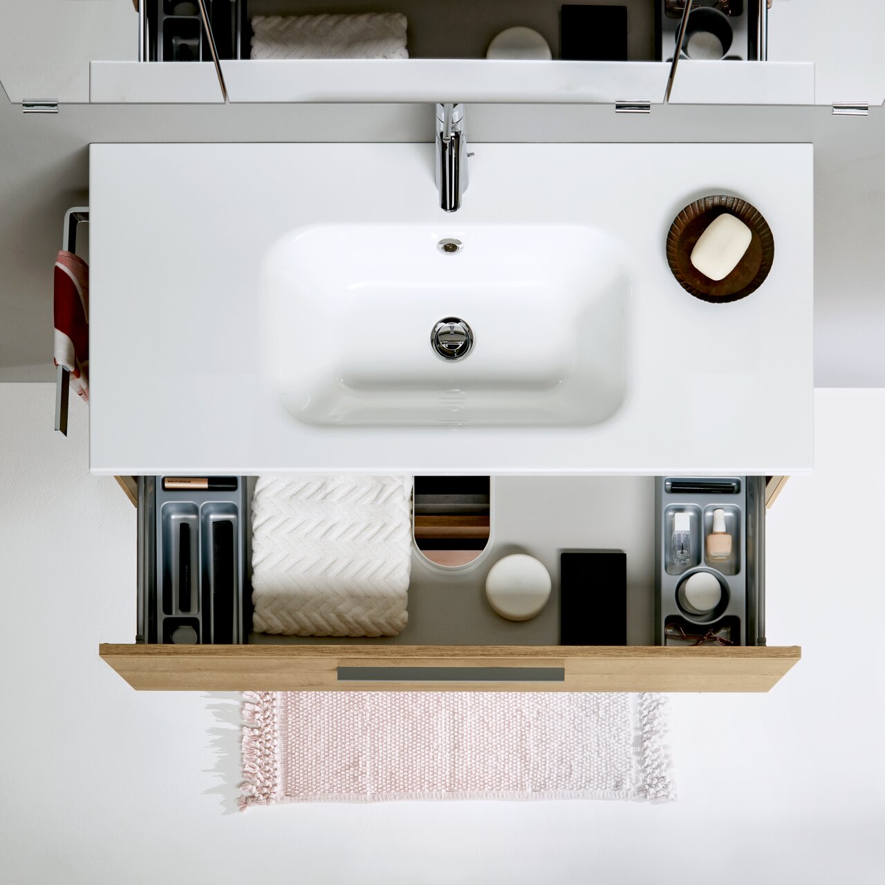 Badezimmerkombination von oben mit Waschbecken, geöffneter Schublade und Accessoires.
