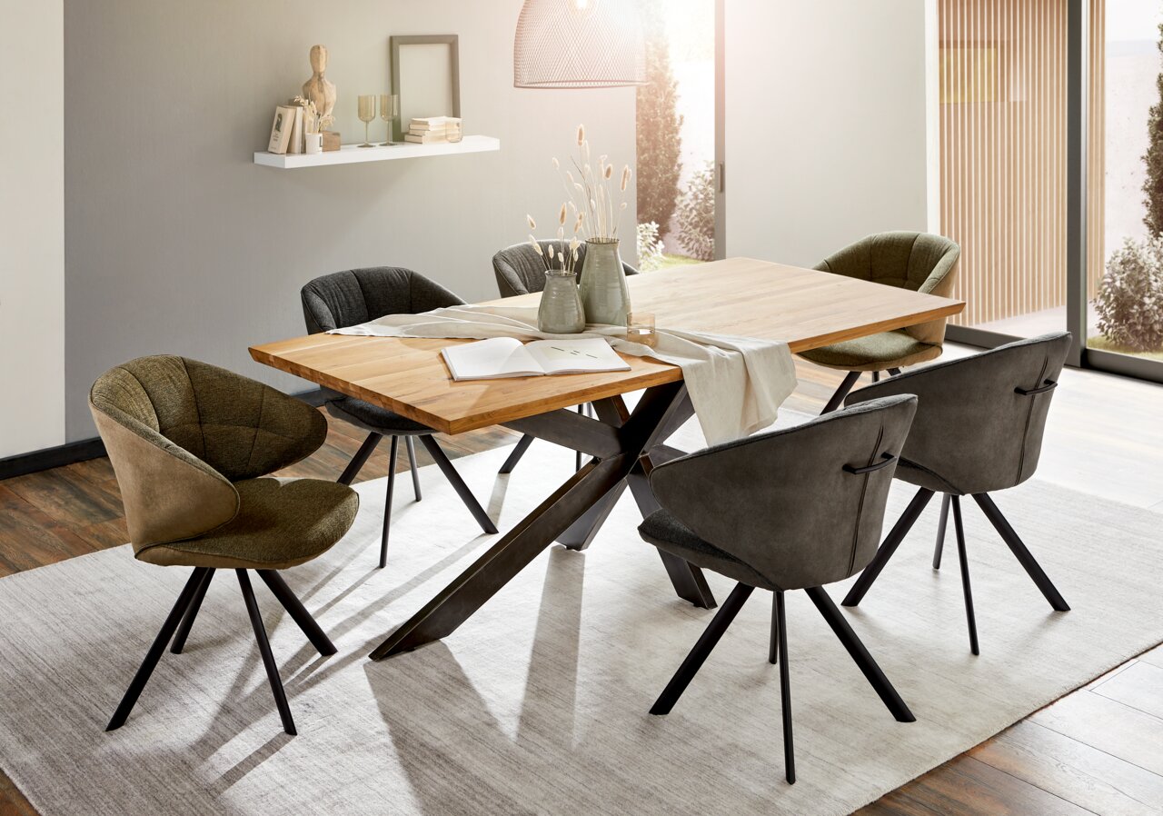 Moderner Esstisch mit Holzplatte und schwarzen Metallbeinen, umgeben von stilvollen Stühlen in einem hellen Esszimmer. Perspektive von schräg oben.