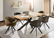 Moderne eettafel met houten blad en zwarte metalen poten, omringd door stijlvolle stoelen in een lichte eetkamer. Aanzicht van schuin bovenaf.