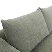 Nahaufnahme einer grauen Sofaecke mit weichen Kissen, seitliche Perspektive.
