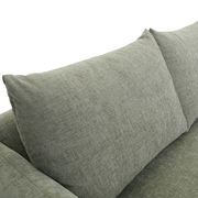 Nahaufnahme einer grauen Sofaecke mit weichen Kissen, seitliche Perspektive.