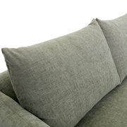 Nahaufnahme einer grauen Sofaecke mit weichen Kissen, seitliche Perspektive.